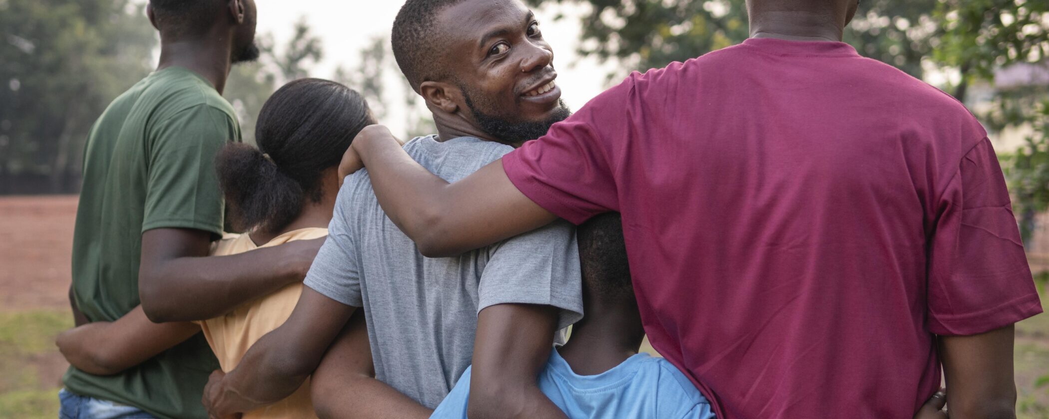 A group of young individuals embracing each other, smiling.